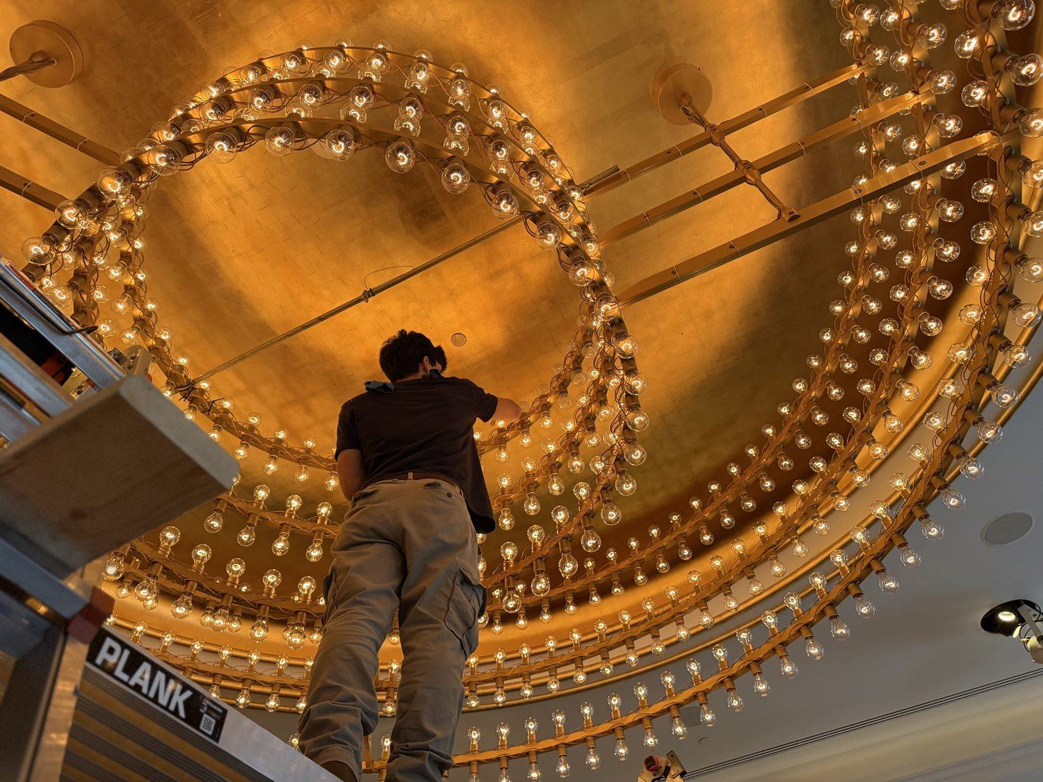 Technician changing bulbs across a large ring fixture